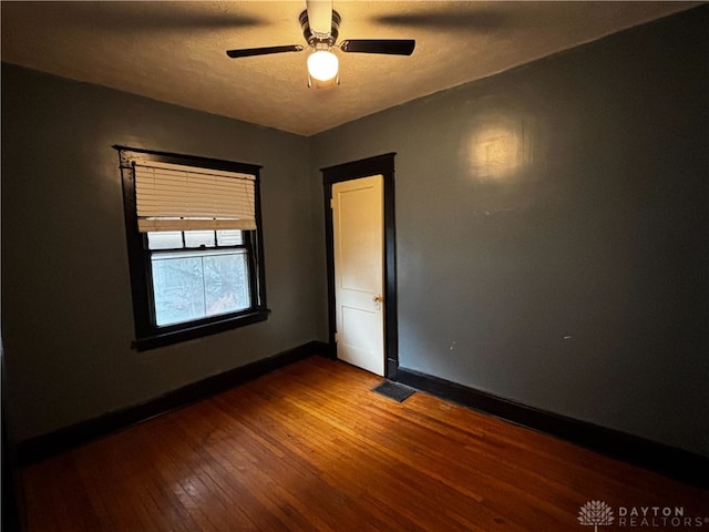 empty room with ceiling fan, wood-type flooring, and a textured ceiling