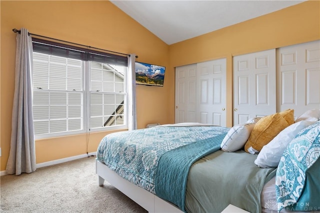 carpeted bedroom with lofted ceiling and two closets