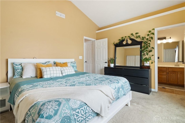 bedroom with lofted ceiling, sink, light carpet, and ensuite bathroom