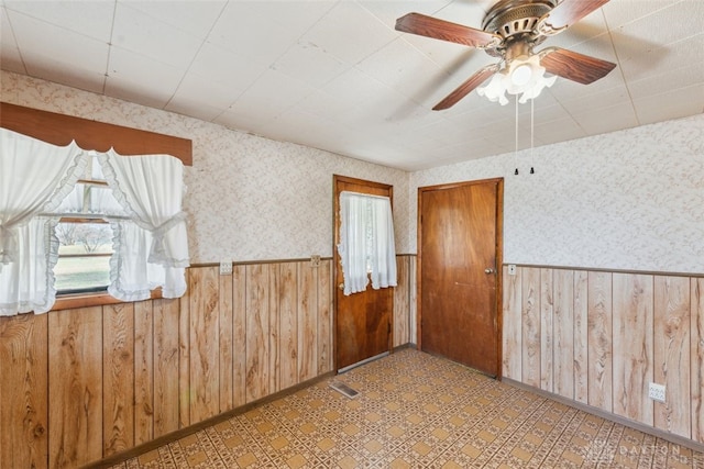 unfurnished room with tile patterned floors, wainscoting, visible vents, and wallpapered walls