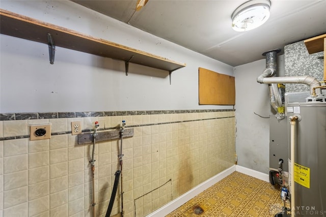 finished basement featuring gas water heater, a wainscoted wall, and tile patterned floors