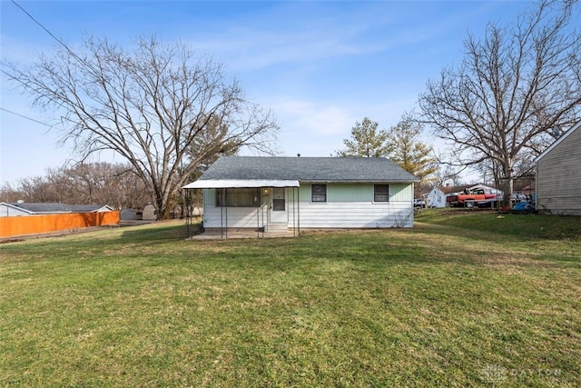 back of house with entry steps, a lawn, and fence