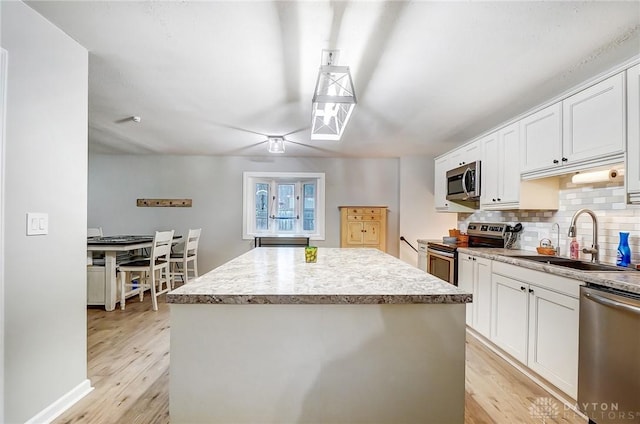 kitchen with appliances with stainless steel finishes, a center island, sink, and white cabinets