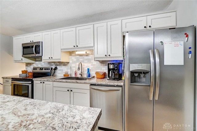 kitchen with stainless steel appliances, sink, white cabinets, and decorative backsplash