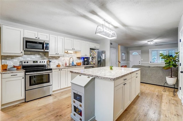 kitchen with white cabinetry, pendant lighting, a kitchen island, and appliances with stainless steel finishes