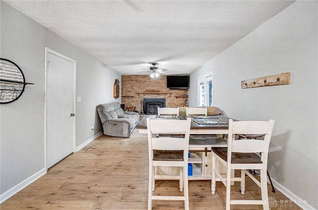 dining room featuring a textured ceiling, ceiling fan, and light wood-type flooring