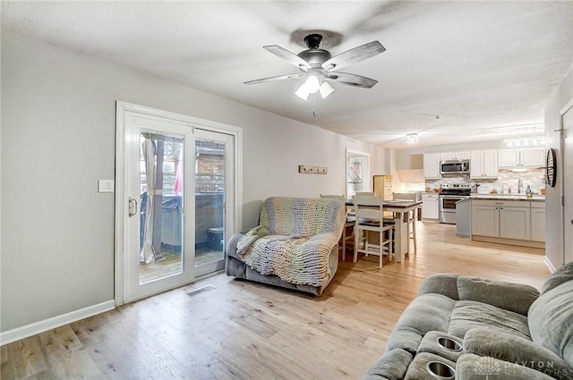 living room with light hardwood / wood-style floors and ceiling fan