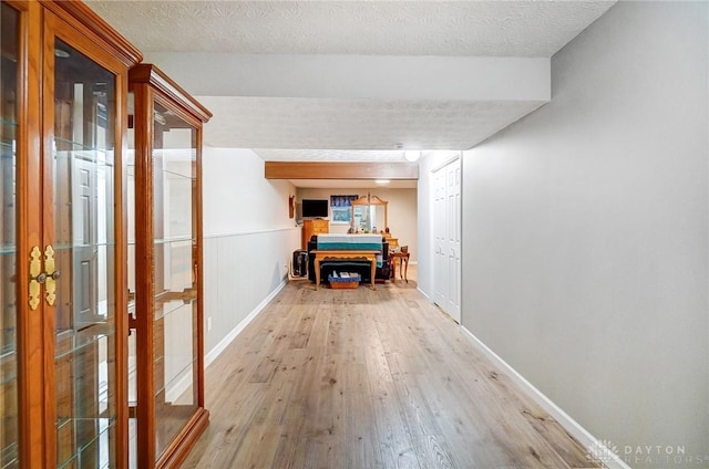 hallway with light hardwood / wood-style flooring and a textured ceiling