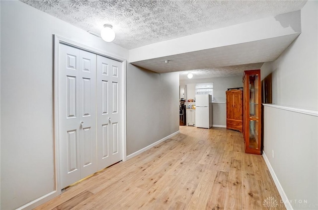 hall featuring a textured ceiling and light hardwood / wood-style flooring