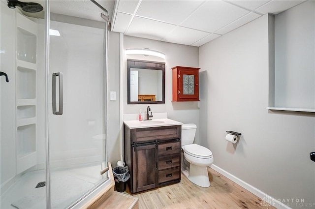 bathroom featuring toilet, an enclosed shower, wood-type flooring, vanity, and a drop ceiling