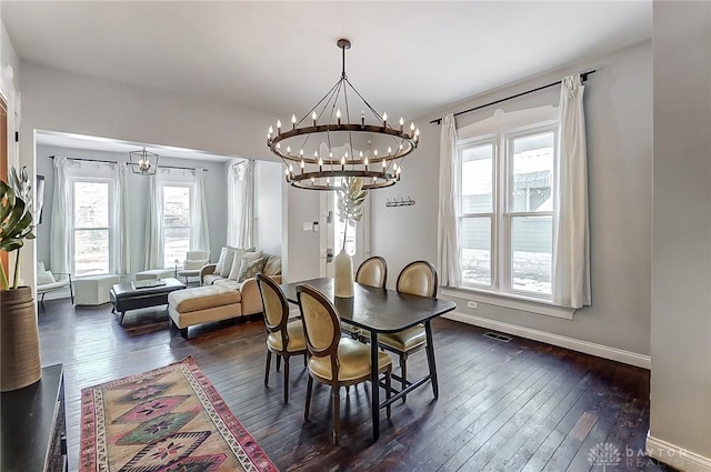 dining space featuring dark wood-type flooring and an inviting chandelier