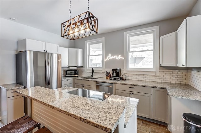 kitchen featuring pendant lighting, appliances with stainless steel finishes, sink, and white cabinets