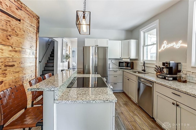 kitchen featuring a kitchen bar, sink, a center island, hanging light fixtures, and appliances with stainless steel finishes