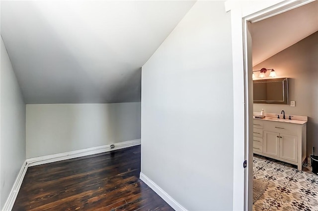 additional living space with vaulted ceiling, dark wood-type flooring, and sink