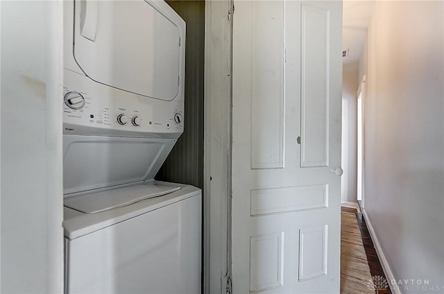 laundry room featuring hardwood / wood-style flooring and stacked washing maching and dryer