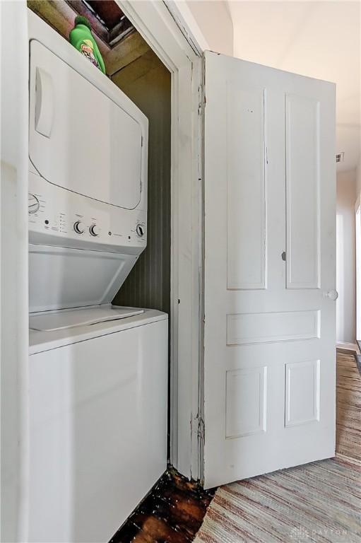 laundry area featuring stacked washer and dryer and hardwood / wood-style flooring