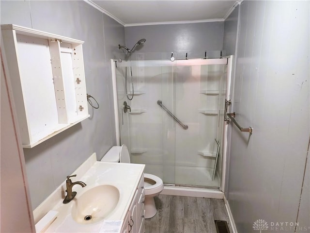 bathroom with toilet, an enclosed shower, wood-type flooring, ornamental molding, and vanity