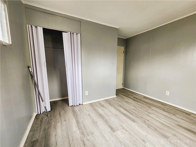 unfurnished bedroom featuring ornamental molding, a closet, and light hardwood / wood-style flooring