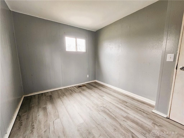 unfurnished room with wood walls and light hardwood / wood-style flooring