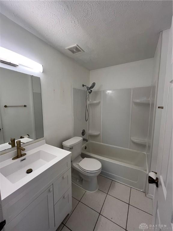 full bathroom with tile patterned floors, toilet, a textured ceiling, vanity, and shower / bath combination