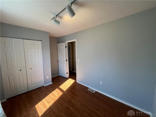 unfurnished bedroom featuring a closet, dark hardwood / wood-style floors, a textured ceiling, and ceiling fan