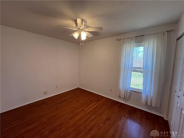 spare room featuring dark wood-type flooring and ceiling fan