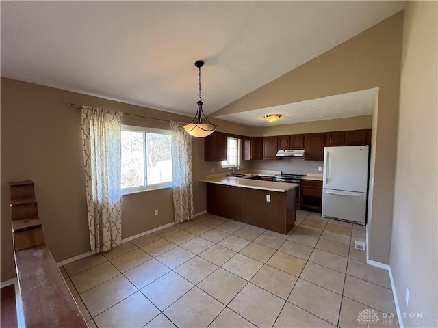 kitchen featuring vaulted ceiling, decorative light fixtures, sink, white fridge, and kitchen peninsula