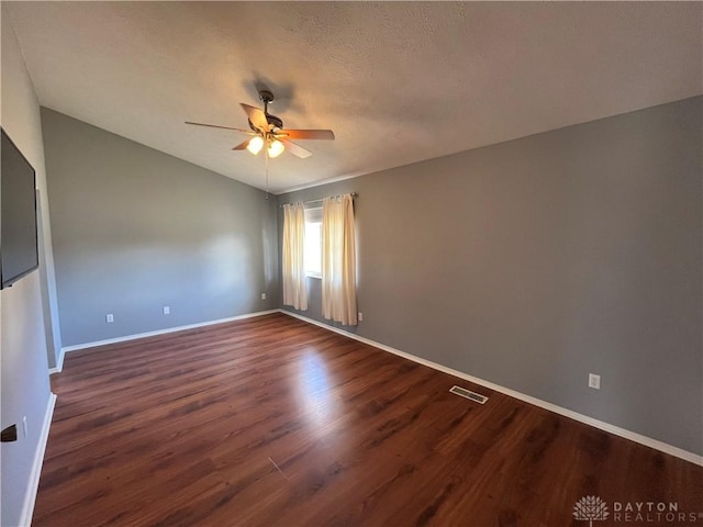 unfurnished room with lofted ceiling, a textured ceiling, dark wood-type flooring, and ceiling fan