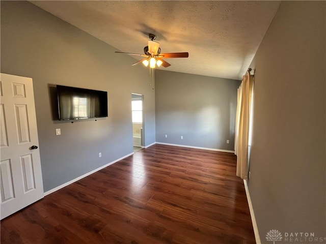 spare room with dark wood-type flooring, ceiling fan, vaulted ceiling, and a textured ceiling