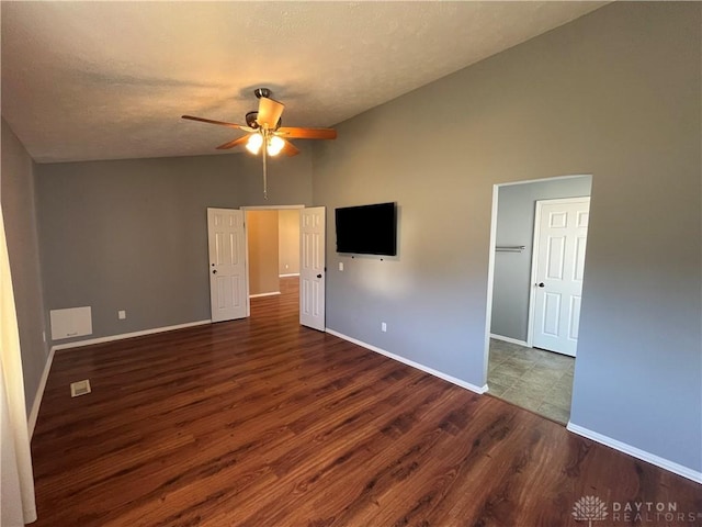 unfurnished bedroom with ceiling fan, vaulted ceiling, dark hardwood / wood-style floors, and a textured ceiling