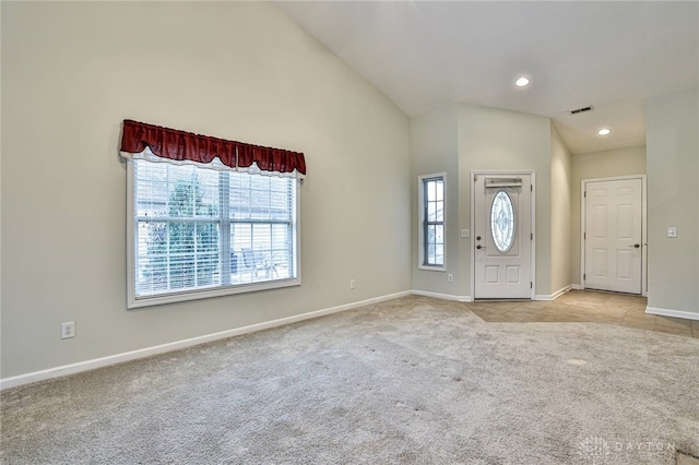 carpeted foyer featuring plenty of natural light and high vaulted ceiling