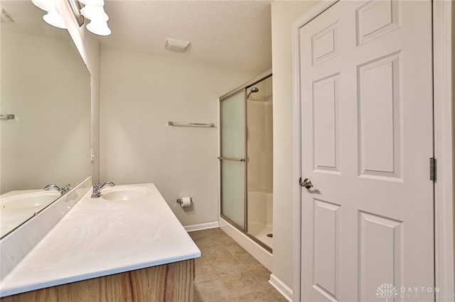 bathroom with tile patterned flooring, vanity, a textured ceiling, and walk in shower