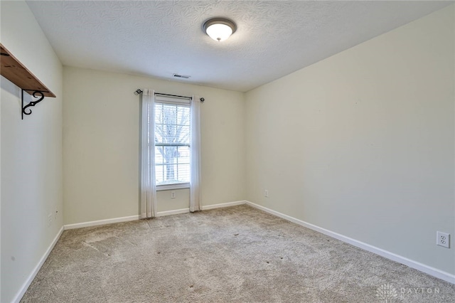 unfurnished room with light colored carpet and a textured ceiling