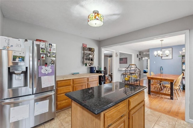 kitchen featuring pendant lighting, a center island, light tile patterned floors, and stainless steel fridge with ice dispenser