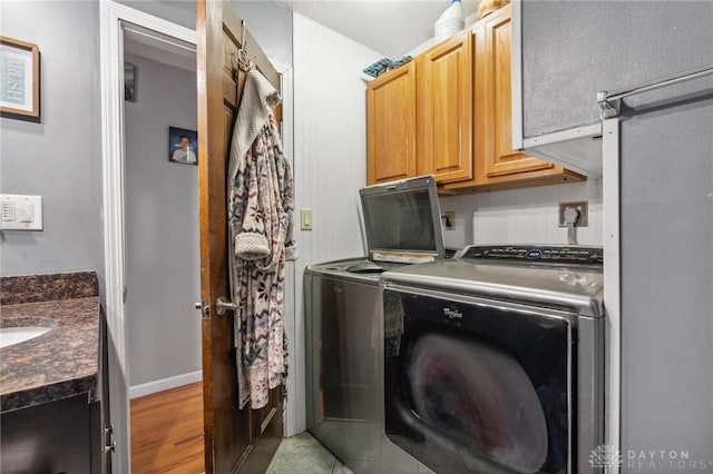 laundry area featuring washing machine and clothes dryer, sink, and light hardwood / wood-style floors