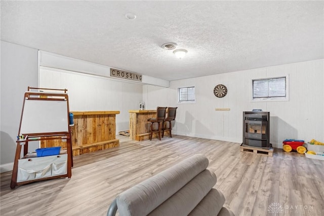 interior space with bar area, a textured ceiling, and light hardwood / wood-style flooring