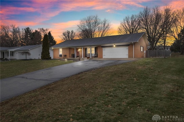 ranch-style house with a garage, a porch, and a yard