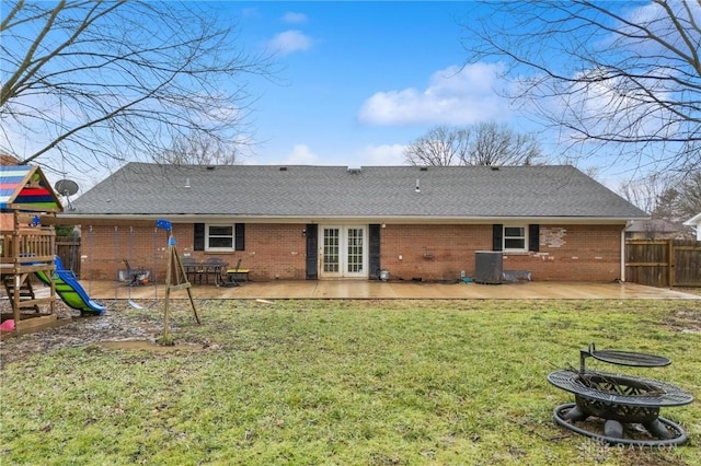 rear view of house featuring a playground, a patio, a lawn, central AC unit, and an outdoor fire pit