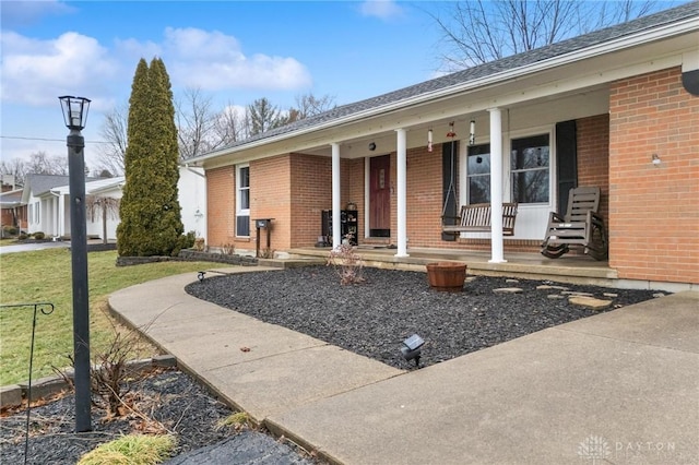 view of exterior entry with a yard and covered porch