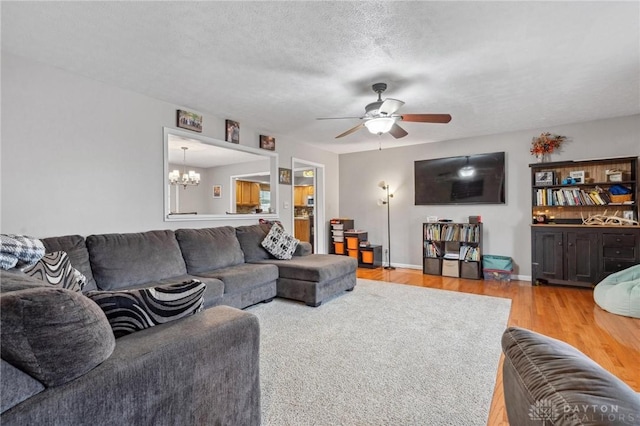 living room with ceiling fan with notable chandelier, a textured ceiling, and light hardwood / wood-style flooring