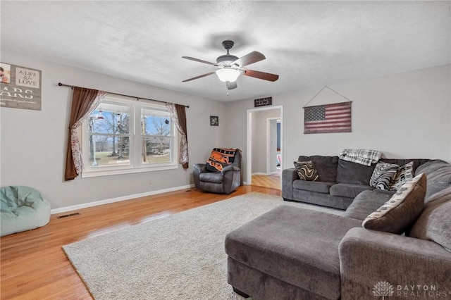 living room with hardwood / wood-style flooring, ceiling fan, and a textured ceiling