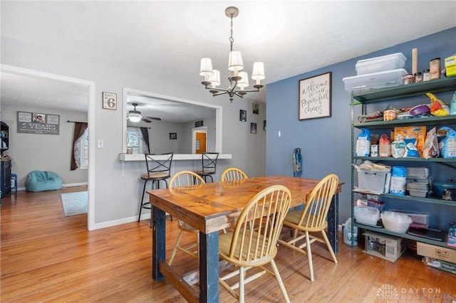 dining space featuring ceiling fan with notable chandelier and light hardwood / wood-style floors