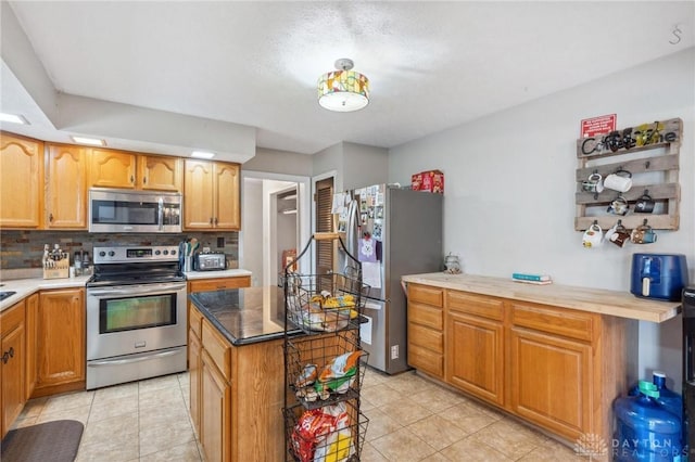 kitchen featuring a kitchen island, appliances with stainless steel finishes, light tile patterned floors, and backsplash