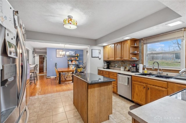 kitchen featuring sink, tasteful backsplash, decorative light fixtures, appliances with stainless steel finishes, and a kitchen island