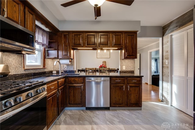 kitchen with dark brown cabinetry, tasteful backsplash, dark stone counters, and appliances with stainless steel finishes