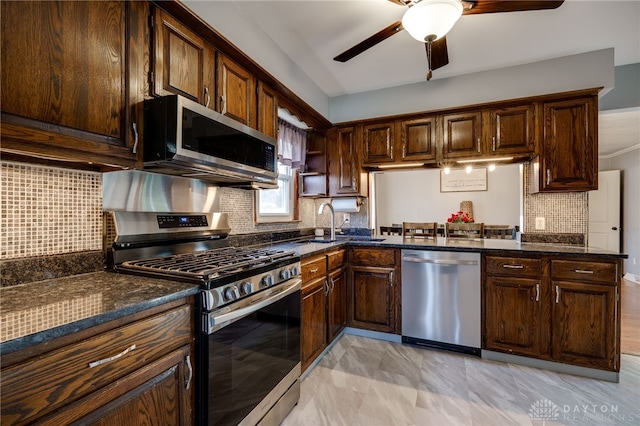 kitchen with dark brown cabinets, appliances with stainless steel finishes, decorative backsplash, and dark stone countertops