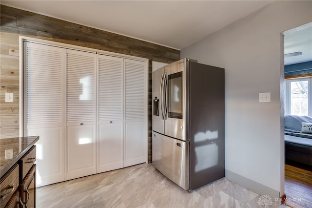 kitchen with stainless steel fridge and dark stone countertops