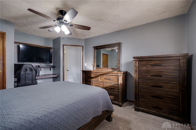 bedroom with ceiling fan, light colored carpet, and a textured ceiling