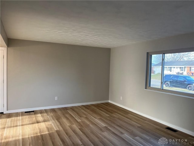 spare room with wood-type flooring and a textured ceiling