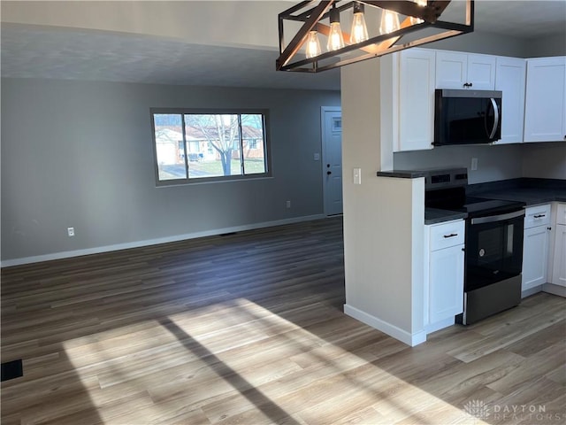 kitchen featuring stainless steel electric range, decorative light fixtures, white cabinetry, a notable chandelier, and light hardwood / wood-style flooring